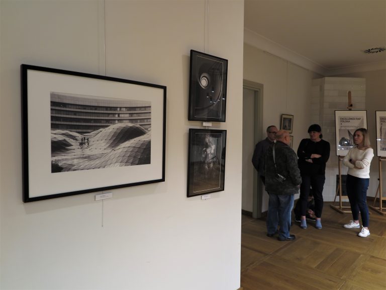 Fotografie na ścianach; osoby zwiedzające wystawę