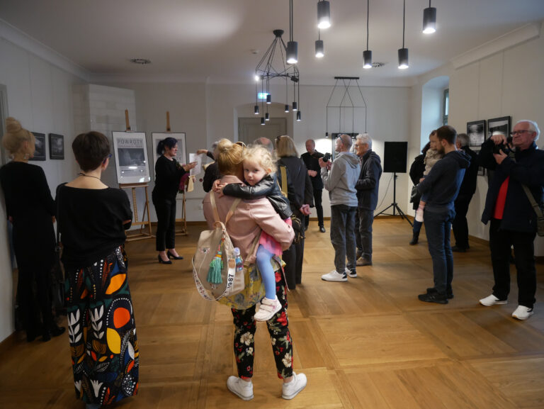Odwiedzający wystawę skupieni na przemówieniu po wyróżnieniu Katarzyny Leszczyńskiej-Kaszuby oraz Adama Sowuli przez Fotoklub RP